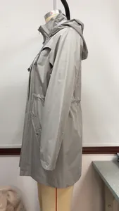 Side view profile of a khaki mid-length hooded zip-up windbreaker raincoat for women.