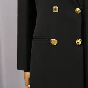 Gros plan d'un blazer noir de créateur avec des boutons dorés sculpturaux ornés.