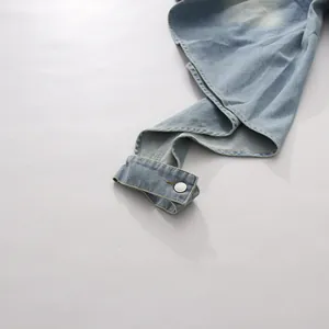 Gros plan sur la taille et le bouton argenté de ce pantalon en jean bleu rétro