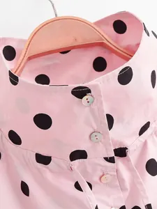 Close-up detail of a pink women's jacket with black polka dots and stand collar design