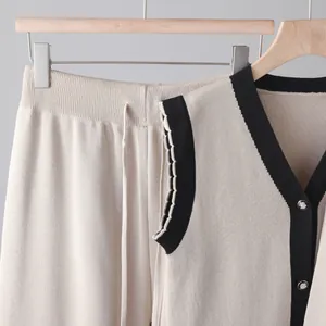 Gros plan sur un ensemble élégant en maille beige 3 pièces avec bordure noire et boutons