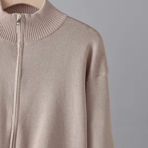 Makro-Detail eines beigen Strick-Cardigans mit silbernem Reißverschluss und Stehkragen