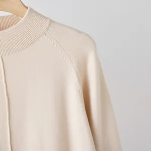 Close-up of beige mock neck sweater with raglan sleeve and ribbed collar detail.
