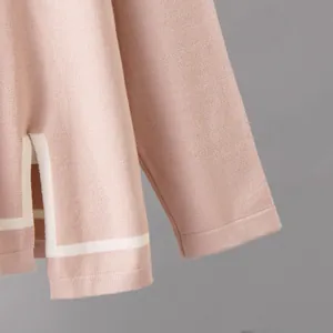 Close-up of pink knitted top detail featuring white contrast stripe and side slit design