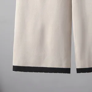 Gros plan de l'ourlet du pantalon en maille beige avec rayure noire et bord festonné