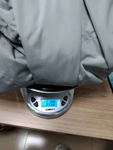 Detailed view of grey hooded zippered raincoat weighing 620 grams on a digital scale