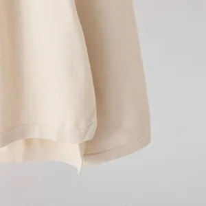 Close-up detail of beige knit sweater hem showing fine ribbed texture and soft fabric