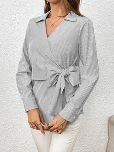 Detail of a black and white striped long sleeve wrap blouse with bow tie waist