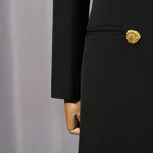Vue détaillée d'un bouton doré gaufré sur un blazer noir de haute qualité pour femmes