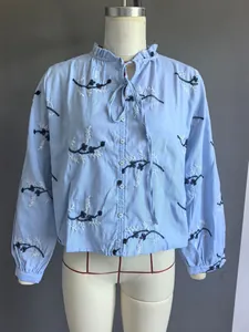 Detailoverzicht van lichtblauw shirt met borduurwerk en ruffelkraag op een paspop