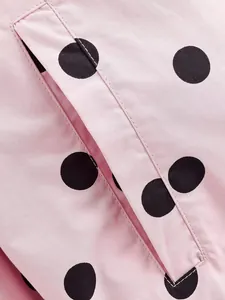 Close-up detail of a pink polka dot jacket showing high-quality stitching on a welt pocket