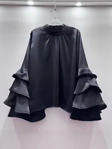 Elegant black satin blouse featuring multi-layered tiered ruffle sleeves and a mock neck