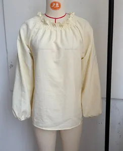 Detail einer lockeren cremefarbenen Bluse mit gerafftem Ausschnitt und Laternenärmeln.