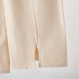 Close-up detail view of elegant beige knitted wide-leg pants featuring a stylish side split hem