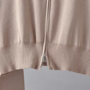 Nahaufnahme der beigen Strickjacke mit silbernem Reißverschluss und Rippenstricksaum.