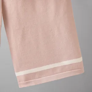 Close-up showing the soft pink knit fabric texture and white contrast stripe on the hem
