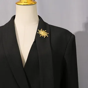 Détail d'une élégante broche soleil dorée épinglée sur une veste de blazer noire sur mesure