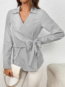 Detail view of women's black and white vertical striped wrap blouse with bow tie waist