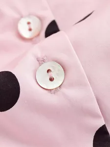 Macro detail of white pearlescent buttons on pink and black polka dot fabric jacket