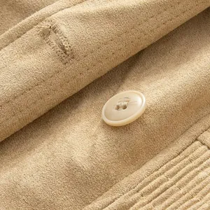 Close-up detail of tan suede jacket featuring a button and fine stitching texture.