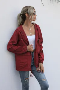 Close-up showing the material of a wine red lightweight hooded rain jacket on model