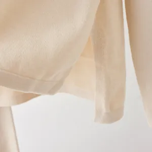 Close-up of a cream-colored knitted sweater showing high-quality side slit detail