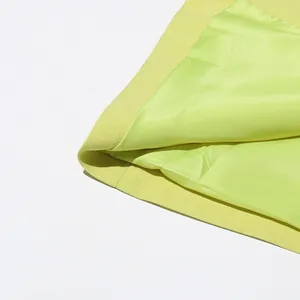 Macro detail of the lime green blazer showing textured outer fabric and silky lining
