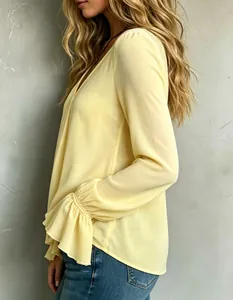 Side detail of elegant yellow V-neck blouse with ruffled pleated cuffs and loose fit.