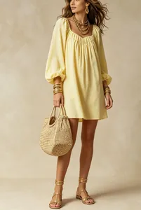Détail d'une robe courte jaune à manches lanternes stylisée avec des accessoires dorés