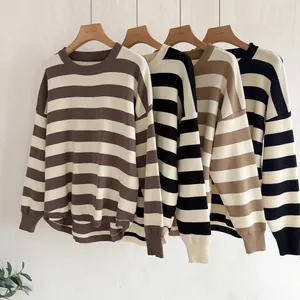 Row of four oversized striped knit sweaters in autumn colors on wooden hangers