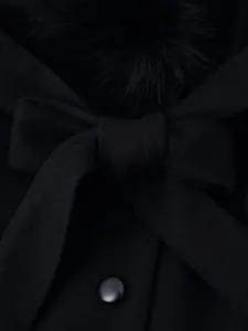 Vue détaillée d'un manteau d'hiver noir avec un grand col en fourrure et un nœud