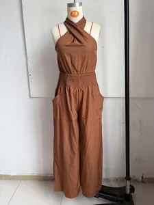 Detail view of brown halter neck jumpsuit showing smocked waist and side pockets.