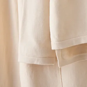 Close-up view of the split hem and ribbed texture on a premium cream knitted two-piece set