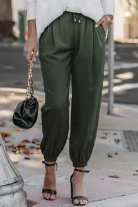 Close-up of dark green high waisted drawstring joggers shown in a street style setting