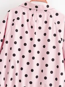 Detailed view of pink fabric with large black polka dots on this stylish woman's jacket.