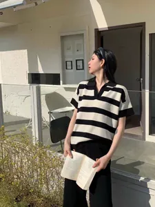 Detailed view of striped polo collar knit top worn by a model in outdoor setting