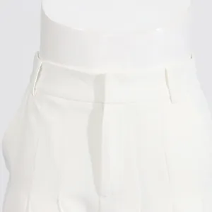 Close-up detail showing the waistline and pleated design of white high-waisted trousers