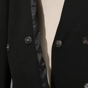 Détail d'un blazer noir avec boutons métalliques argentés et doublure de haute qualité