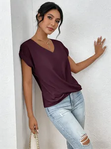 Woman wearing an elegant burgundy V-neck T-shirt with twist hem detail against a white wall