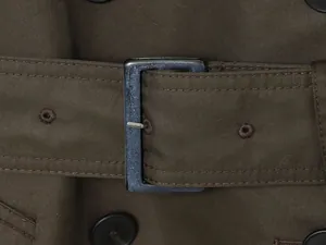 Vue macro de la boucle en métal bleu et de la ceinture olive d'un trench pour femme