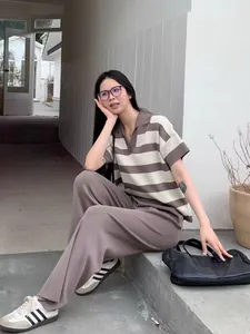 Model wearing striped polo knit top and brown wide-leg pants in a modern outdoor setting