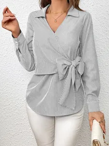 Detailed view of the side bow and vertical stripes on this elegant wrap shirt top.