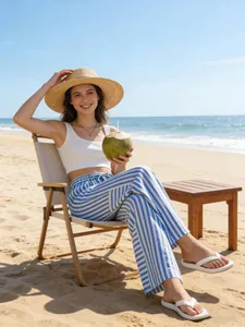 Detailed lifestyle view of women's blue and white striped high-waist wide-leg pants on beach