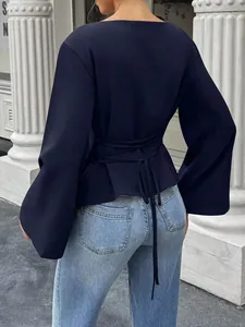 Detailed back view of navy blue boat neck blouse featuring waist-tie and flared long sleeves