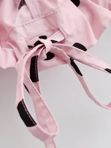 Close-up of pink polka dot jacket detailing the drawstring bow and fabric texture.