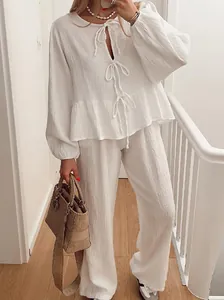 Detail view of a white two-piece lounge set with lantern sleeves and front tie closure.