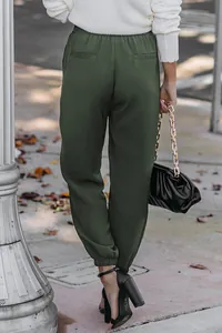 Back view of dark green high waisted cuffed jogger pants for women in a street setting