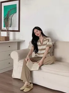 Model wearing a striped polo knit top and brown wide-leg pants in a cozy indoor setting