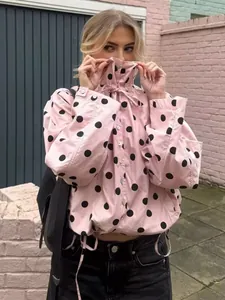 Detailed view of pink polka dot jacket featuring high drawstring collar and button closure