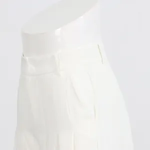 Detailed view of the waist, pleats and side pocket on white wide-leg trousers